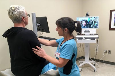 Nurse examining a patient sitting on the table surrounded by medical equipment